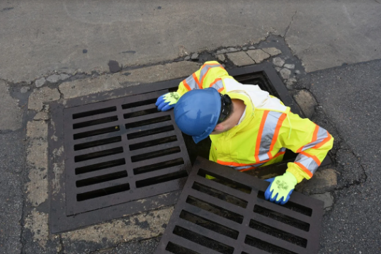 worker in sewer opening