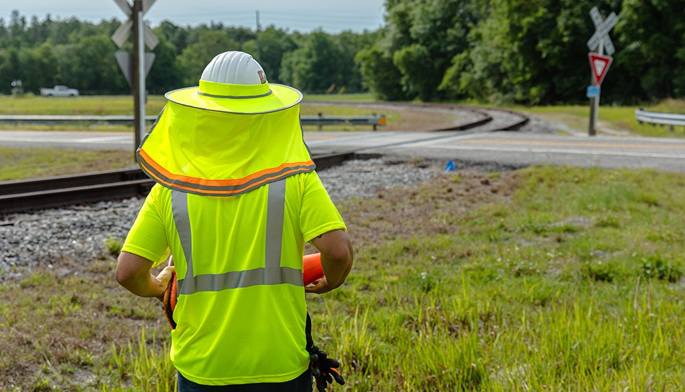 Worker near railroad wearing hivis shirt and sun shade